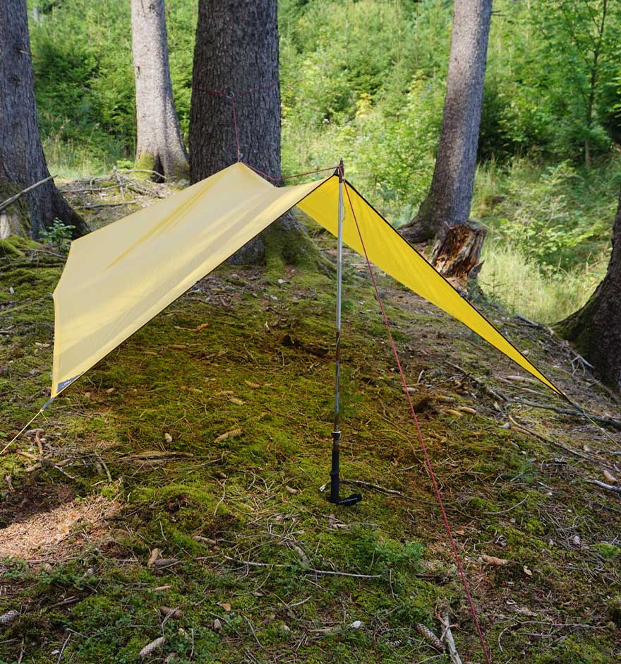 Gelbes Tarp steht aufgespannt im Wald